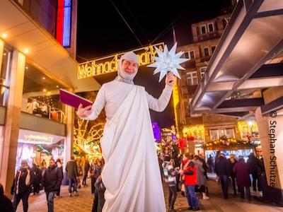 Stelzenläufer mit lila Bibel, Leuchtstern und weißem Gewand